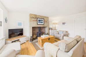 A cozy living room with a fireplace, a television, and comfortable seating. - Host & Stay | Dove Cottage (Warkworth)