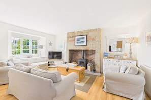 A modern living room with a fireplace, sofas, a television, and a wooden chest. - Host & Stay | Dove Cottage (Warkworth)
