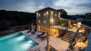 A stone building with a swimming pool, outdoor seating, and a staircase leading to a balcony. - Villa Mila - Makarska by Villas Guide (Zmijavci)