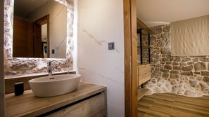 A bathroom with a stone wall, a wooden vanity, a large mirror, and a bathtub. - Villa Mila - Makarska by Villas Guide (Zmijavci)