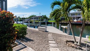 A marina with docked boats, a wooden walkway, and palm trees. - Waterfront 3 Bed Playground in Paradise Awaits (Marco Island)