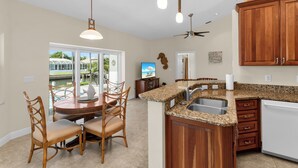 A kitchen with wooden cabinets, a granite countertop, and a built-in dishwasher. - Waterfront 3 Bed Playground in Paradise Awaits (Marco Island)