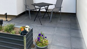 A patio with a table and chairs, a window, and a hanging light fixture. - Apartment 'Zum Kölpiensee' with Shared Terrace, Shared Garden and Wi-Fi (Peenemünde)