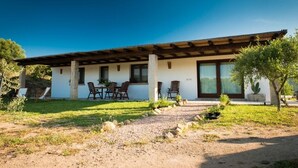A modern house with a patio, outdoor seating, and a well-maintained garden. - Peaceful country house few minutes from the sea (Sardegna)