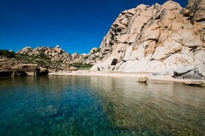 A clear blue pool surrounded by rocky terrain and a clear sky.