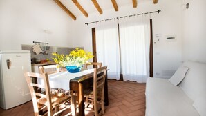 Une pièce de taille modeste comprenant une table à manger, des chaises, un lit et un coin cuisine.