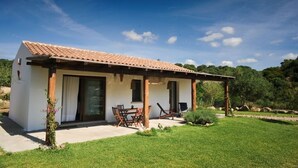 Une maison de plain-pied avec un toit en tuiles, une terrasse couverte et une pelouse.