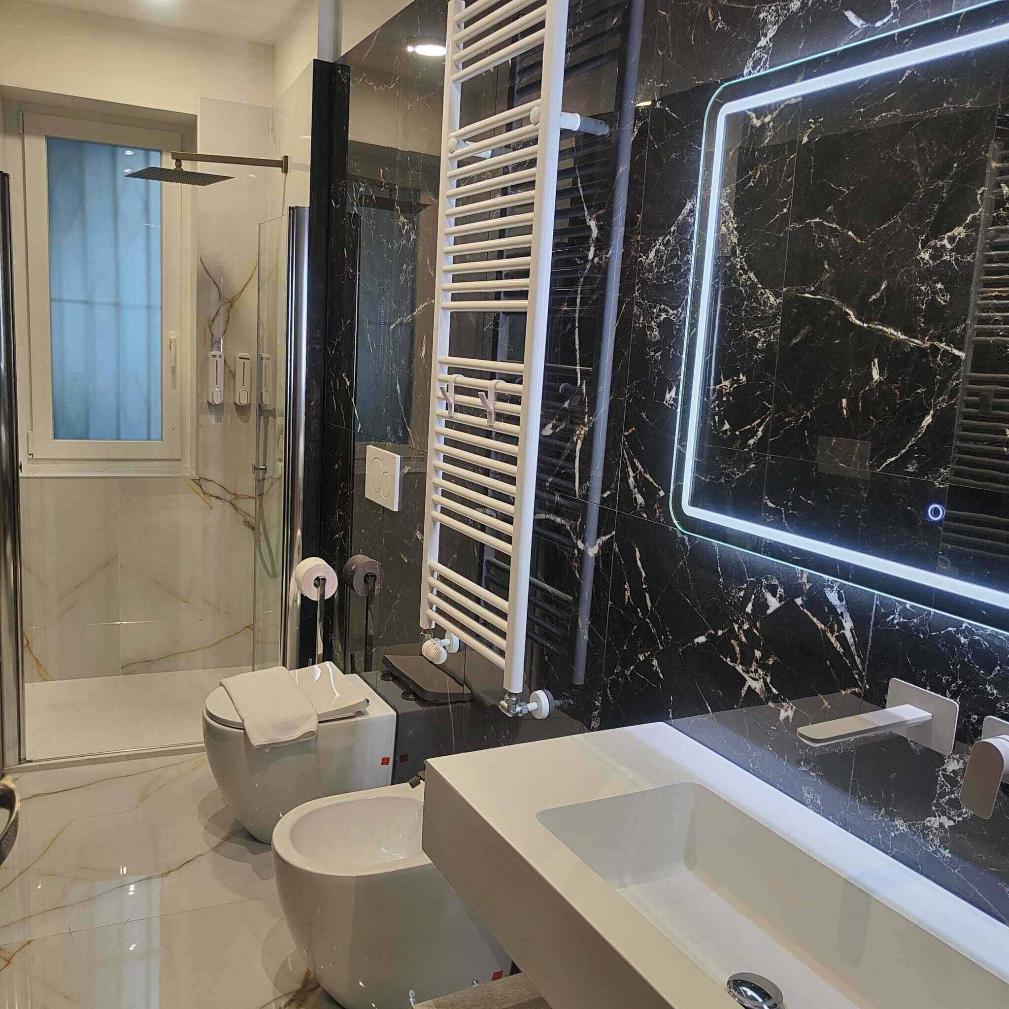 A modern bathroom with a large mirror, a bathtub, a toilet, and a shower area.