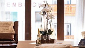 A cozy seating area with a brown leather chair, a small table with a bottle, two glasses, and a plant. - Apartment Sofi- Inspiringplaces Zermatt (Zermatt)