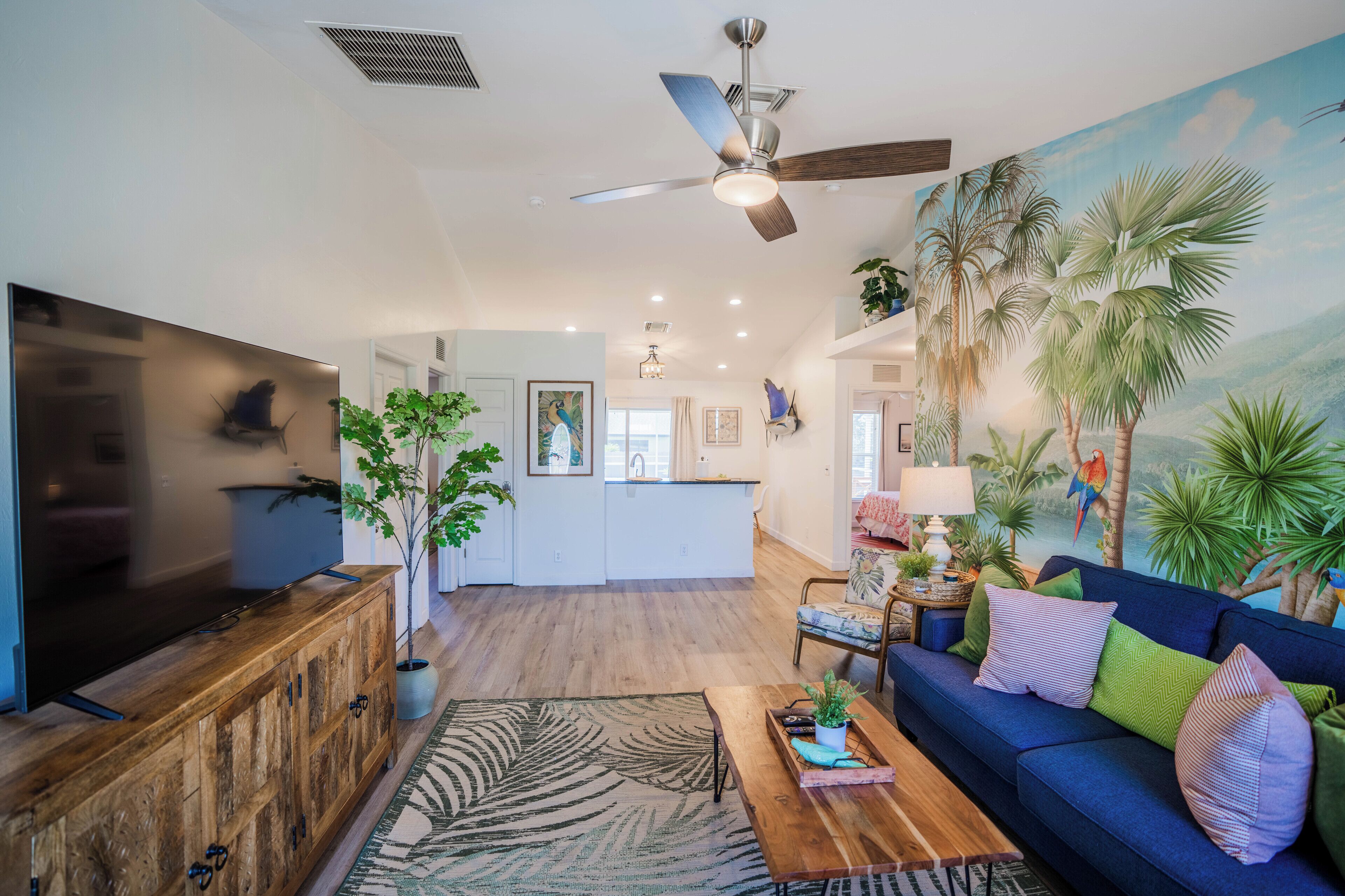 A spacious living area with a wooden entertainment unit, a blue sofa, a coffee table, and a large flat-screen TV.