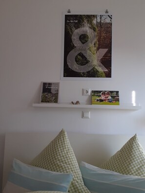 A bedroom with a bed, pillows, a shelf with books, and a poster on the wall. - Room 'No. 2' with Shared Terrace, Shared Garden and Wi-Fi (Bad Urach)
