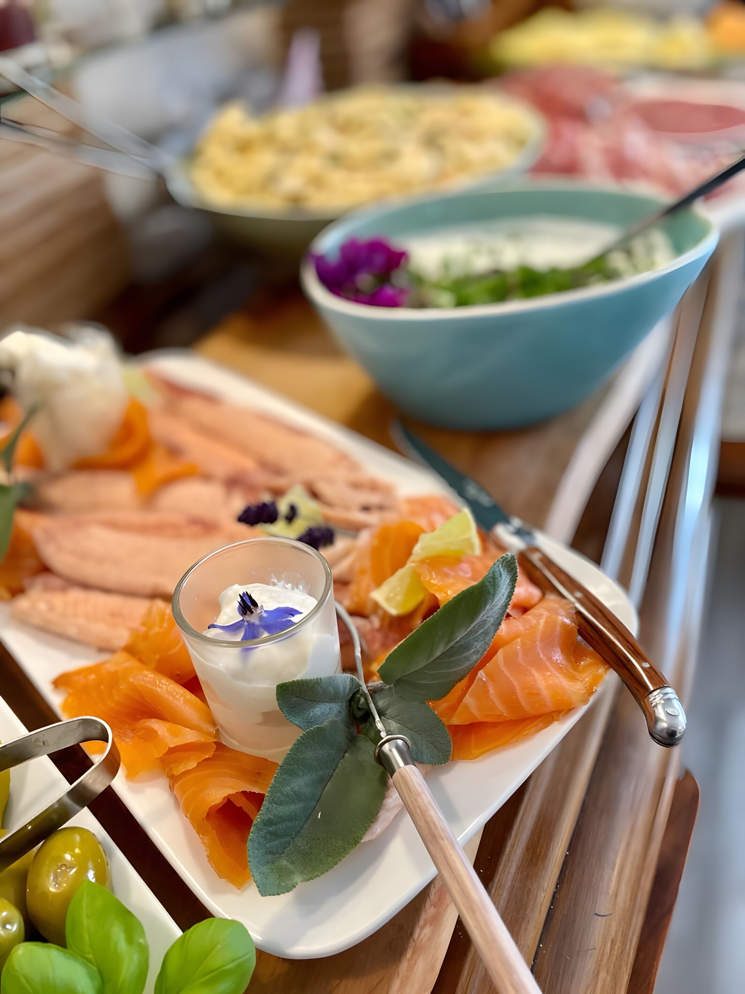 A plate of smoked salmon with a small bowl of cream and a decorative leaf.