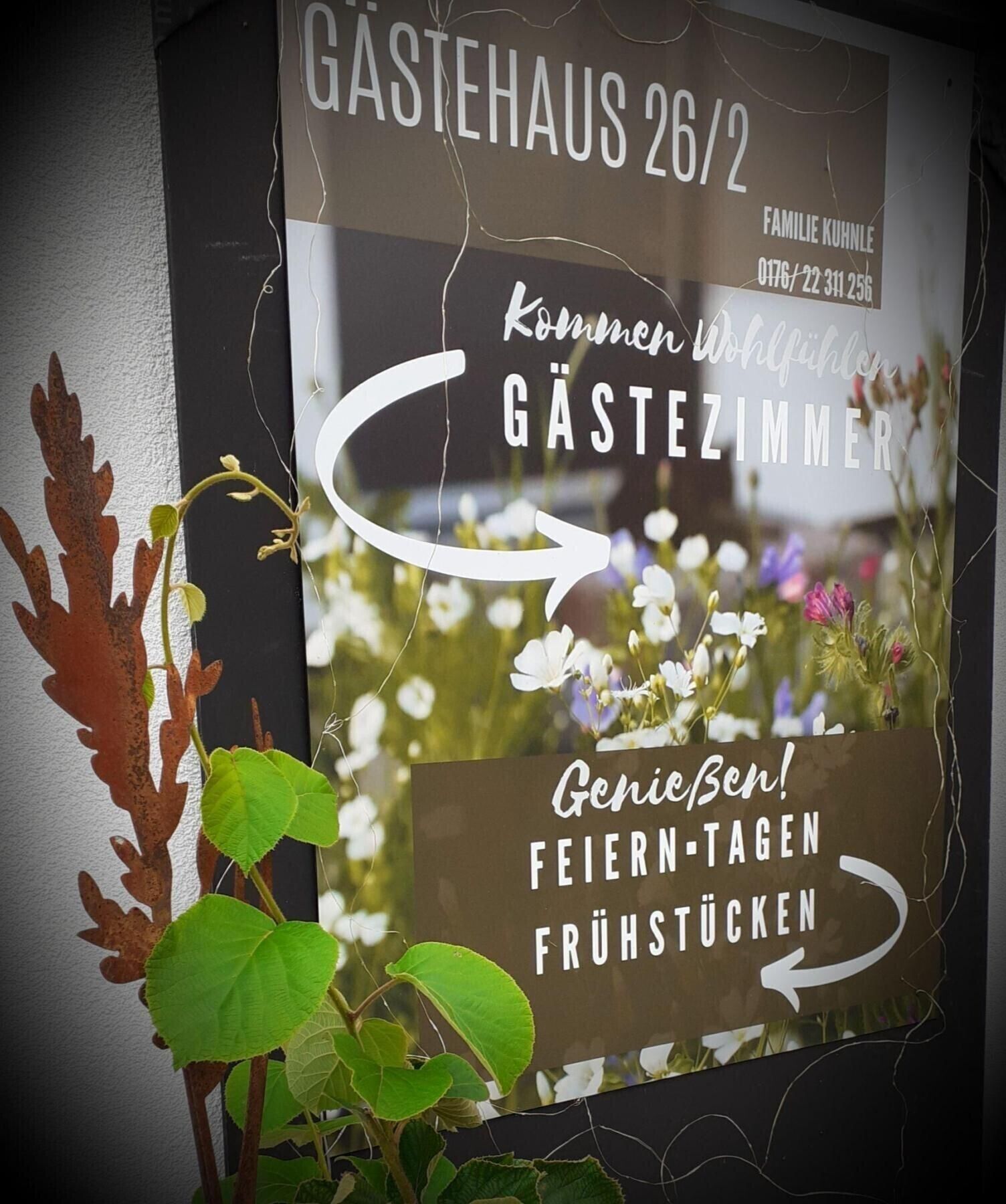 En skylt för Gastehaus 26/2, som visar att det är ett familjeägt företag och anger kontaktuppgifter.