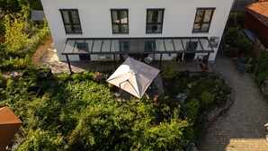 A modern two-story house with a glass balcony, surrounded by lush greenery. - Room 'No. 4' with Shared Terrace, Communal Garden and Wi-Fi (Bad Urach)
