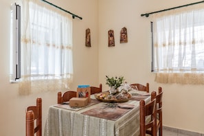 Un comedor con una mesa dispuesta para cuatro, un florero con flores y un cuadro en la pared.