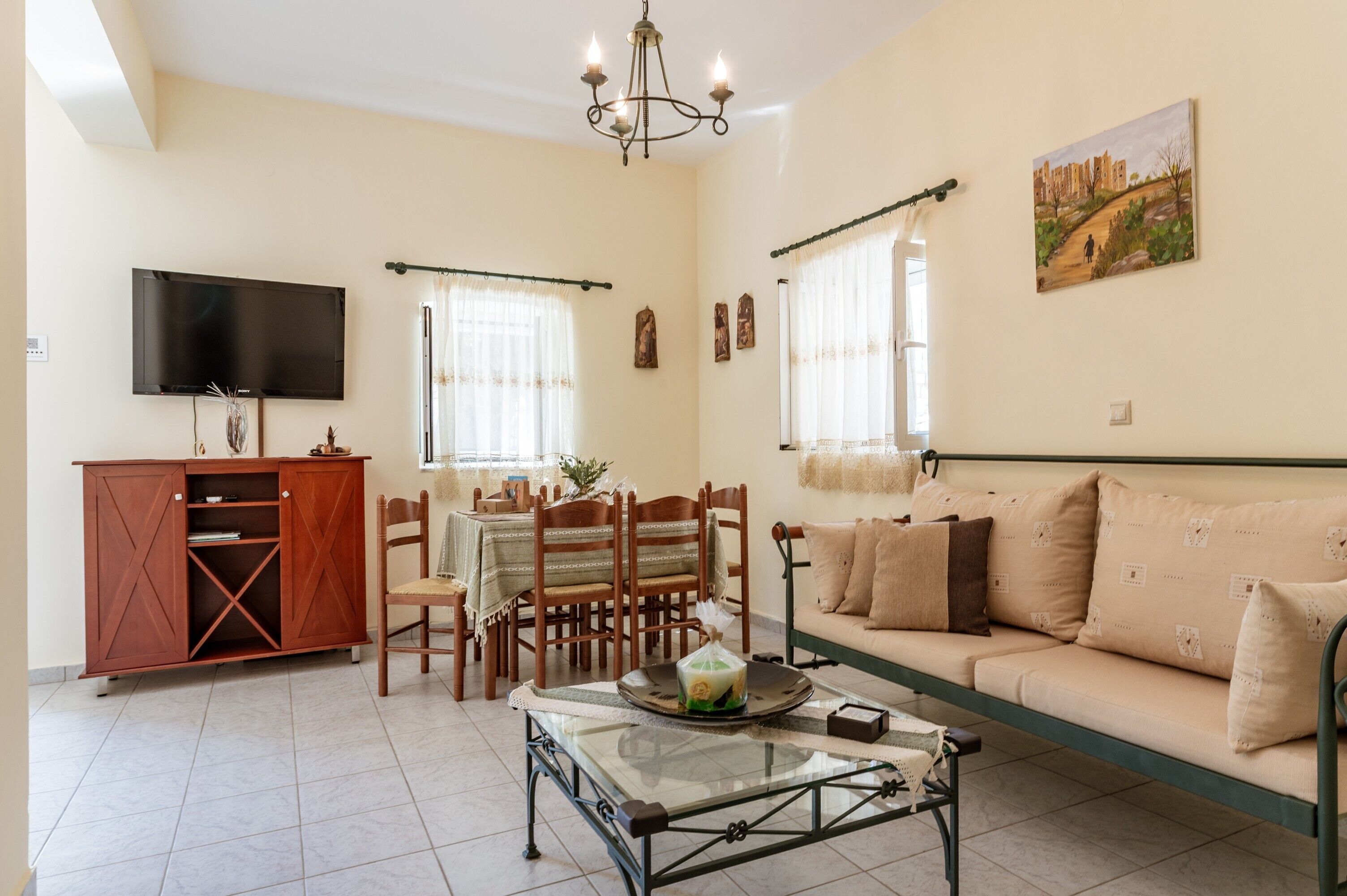 A living room with a sofa, TV, dining table, chairs, and a cabinet.