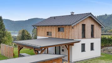 Ein modernes, zweistöckiges Haus mit geneigtem Dach, Holzverkleidung und einem flachen Anbau.