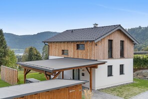 Una casa moderna de dos pisos con techo inclinado, revestimiento de madera y una extensión de techo plano.