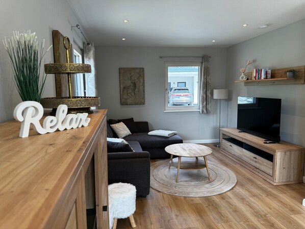 Un salon moderne avec un canapé, un téléviseur, une table basse en bois et un vase décoratif.