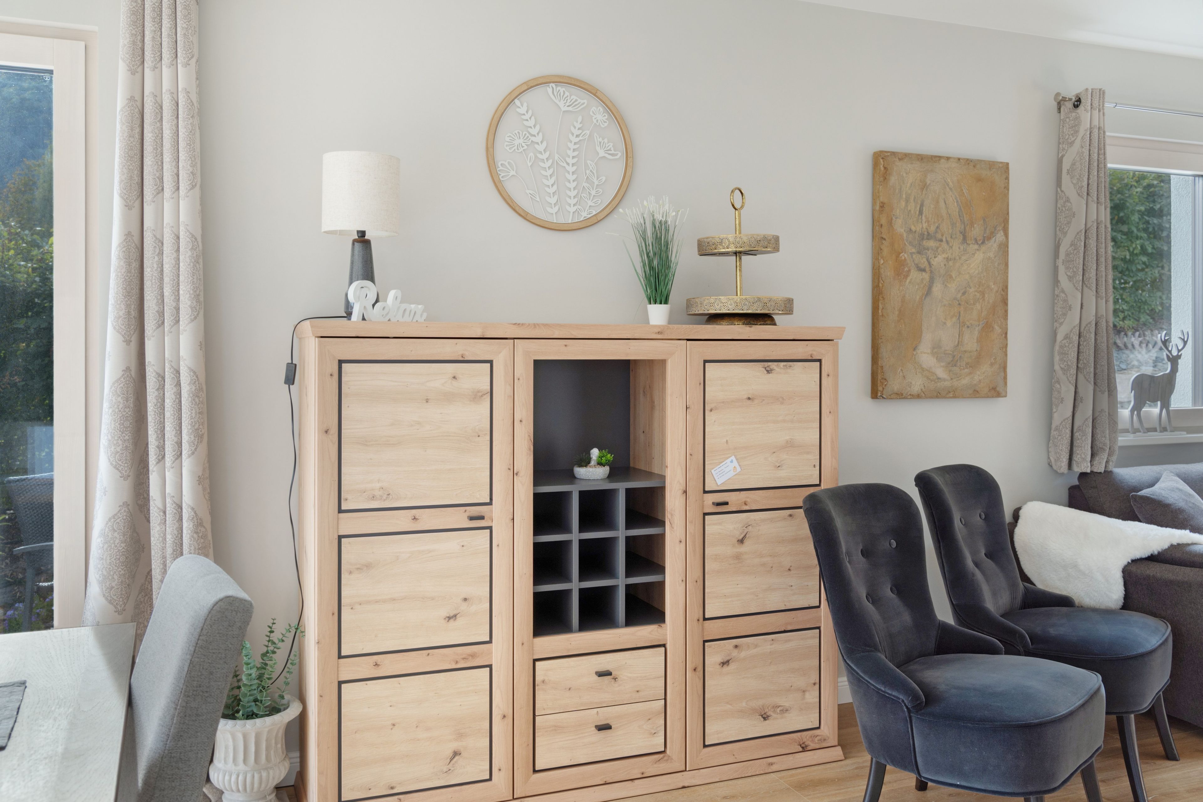 A living room with a wooden cabinet, two armchairs, a lamp, and a painting on the wall.