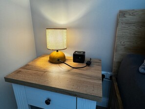 Una mesita de noche con una lámpara, un altavoz y un cajón.