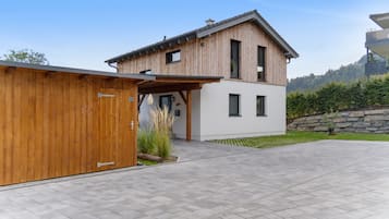 A modern two-story house with a wooden exterior and a stone wall.