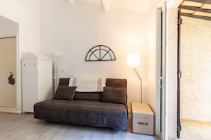 Una habitación con cama, armario, lámpara y puerta que da a un balcón.