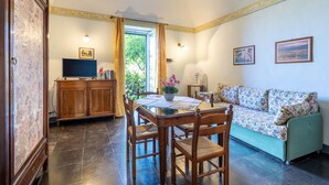 A dining area with a table, chairs, a cabinet, and a television. - Villa Aguglie - Suite Dalia (Modica)