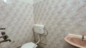 Ein kleines Badezimmer mit gefliesten Wänden, einer Toilette, einem Waschbecken und einem Mülleimer.