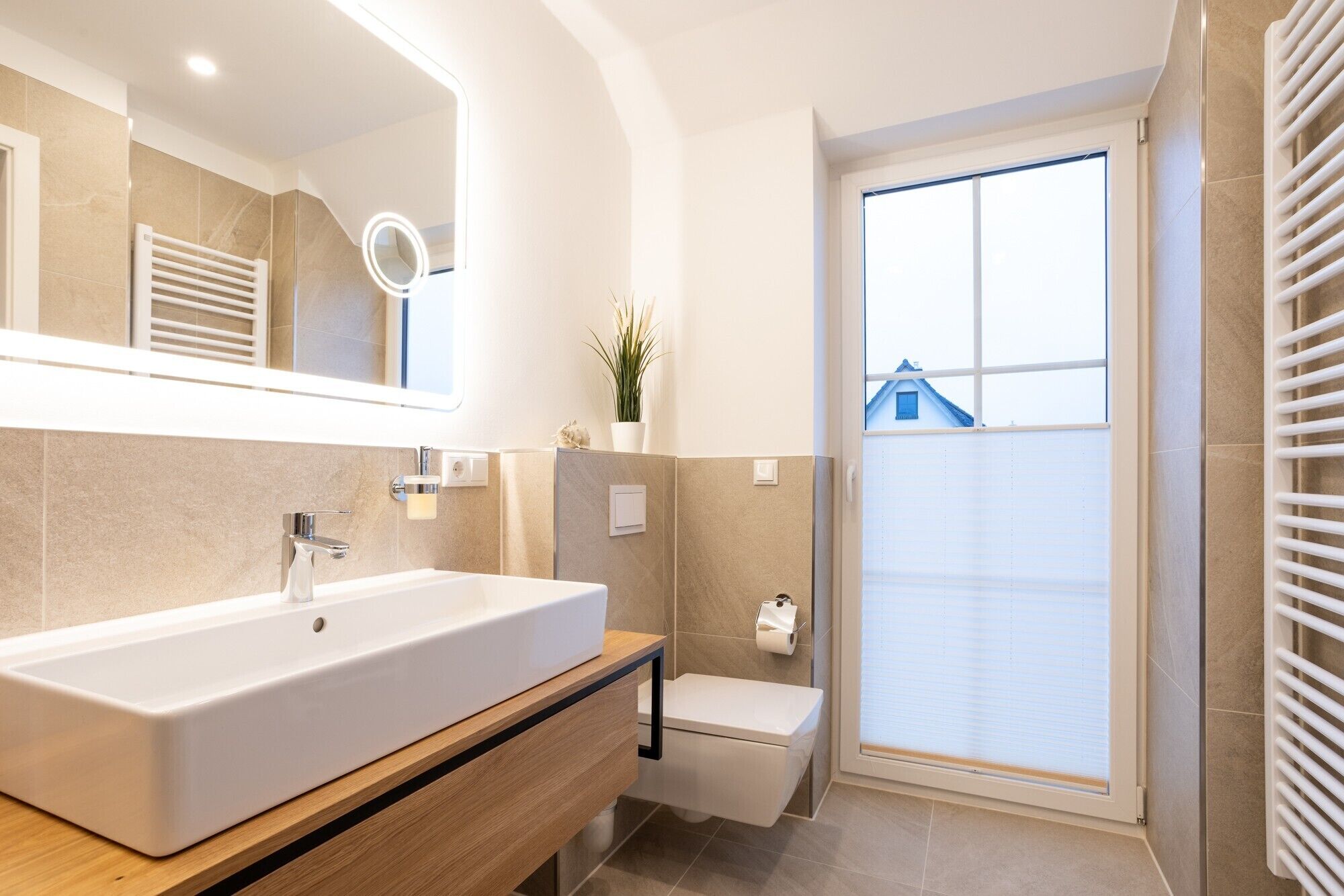 Ein modernes Badezimmer mit einem großen Waschbecken, einem Spiegel und einer Toilette.