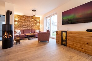 A modern living room with a fireplace, a sofa, a coffee table, a wooden cabinet, and a large window.