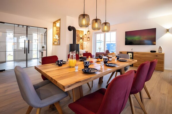 A modern dining area with a wooden table, red chairs, and pendant lights.