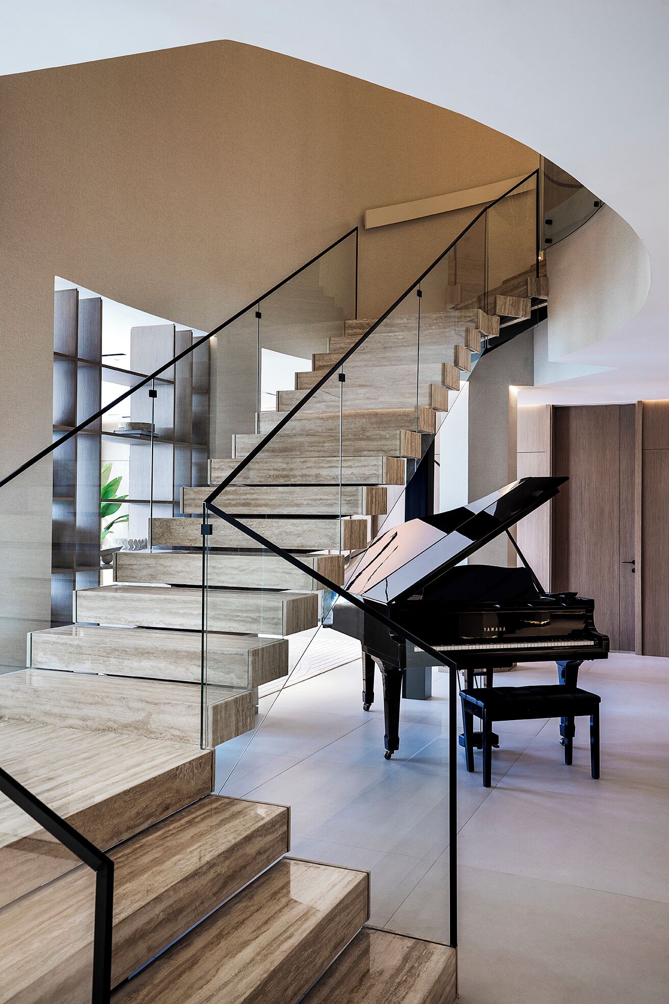 Een vleugel in een ruim, modern interieur met een opvallend trappendesign.
