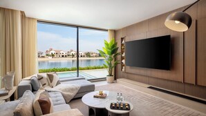 A modern living room with a large TV, comfortable seating, a view of a body of water, and a potted plant. - Villa Portofino by Luxury Explorers Collection (Dubai)