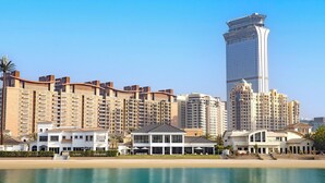 A coastal hotel with multiple high-rise buildings, a beachfront, and a clear sky. - Villa Portofino by Luxury Explorers Collection (Dubai)