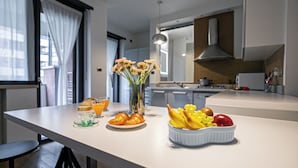 A modern kitchen with a clean, minimalist design, featuring a central island with breakfast items and a vase of flowers. - Italianway Comfort - Bergamo 11 (Milan)