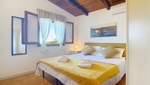 A hotel room with a bed, a nightstand, a lamp, and a painting on the wall. - Apartment 'La Mignola - Bilo 2' with Shared Garden, Wi-Fi and Air Conditioning (Vieste)