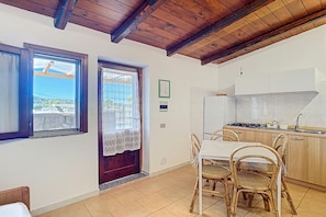 A kitchen with wooden cabinets, a dining table with chairs, and a view through a window.