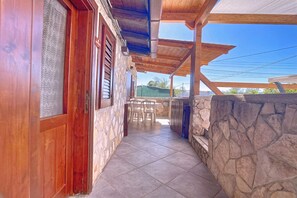 A covered outdoor area with stone walls, wooden beams, and a tiled floor.