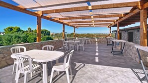 An outdoor patio with tables and chairs, a stone wall, and a view of the landscape. - Apartment 'La Mignola - Quadri 6' with Private Terrace, Wi-Fi and Air Conditioning (Vieste)