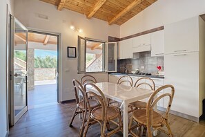 A modern kitchen with white cabinets, a dining table with chairs, and a view to an outdoor area. - Apartment 'La Mignola - Quadri 6' with Private Terrace, Wi-Fi and Air Conditioning (Vieste)