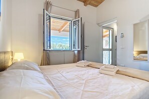A hotel room with a bed, a window, a door, a mirror, and a lamp. - Apartment 'La Mignola - Quadri 6' with Private Terrace, Wi-Fi and Air Conditioning (Vieste)