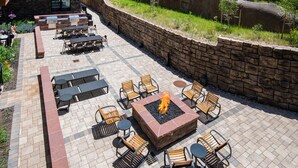 An outdoor patio with stone walls, a fire pit, and seating arrangements. - New Mtn Modern with Luxurious Amenities | F305 (Avon)
