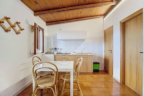 Une cuisine de taille réduite avec un coin repas, un plafond en bois et un revêtement de sol carrelé.