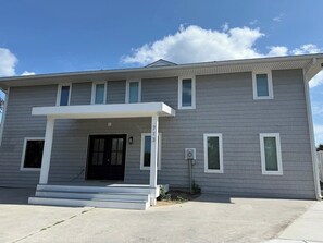 A two-story residential building with a front porch, a black front door, and a small window on the ground floor.