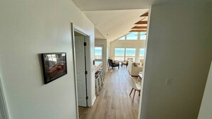 Een gang die leidt naar een woonruimte met uitzicht op de omgeving, een deur en een lijst met een afbeelding aan de muur.