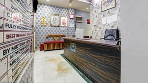 Un espace d’accueil avec un comptoir de réception en bois, un ventilateur de plafond et un mur orné de divers panneaux et de tableaux encadrés.