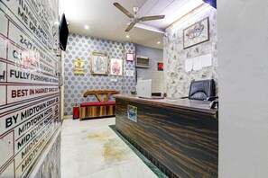 Un'area reception con una scrivania in legno, una ventola a soffitto e una parete con diversi cartelli e quadri incorniciati.