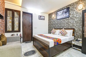 Une chambre à coucher comprenant un lit, un canapé, une table de chevet, une lampe fixée au mur et une porte.