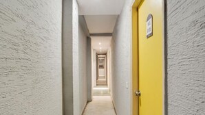 Un couloir étroit aux murs texturés, avec une porte jaune au fond.